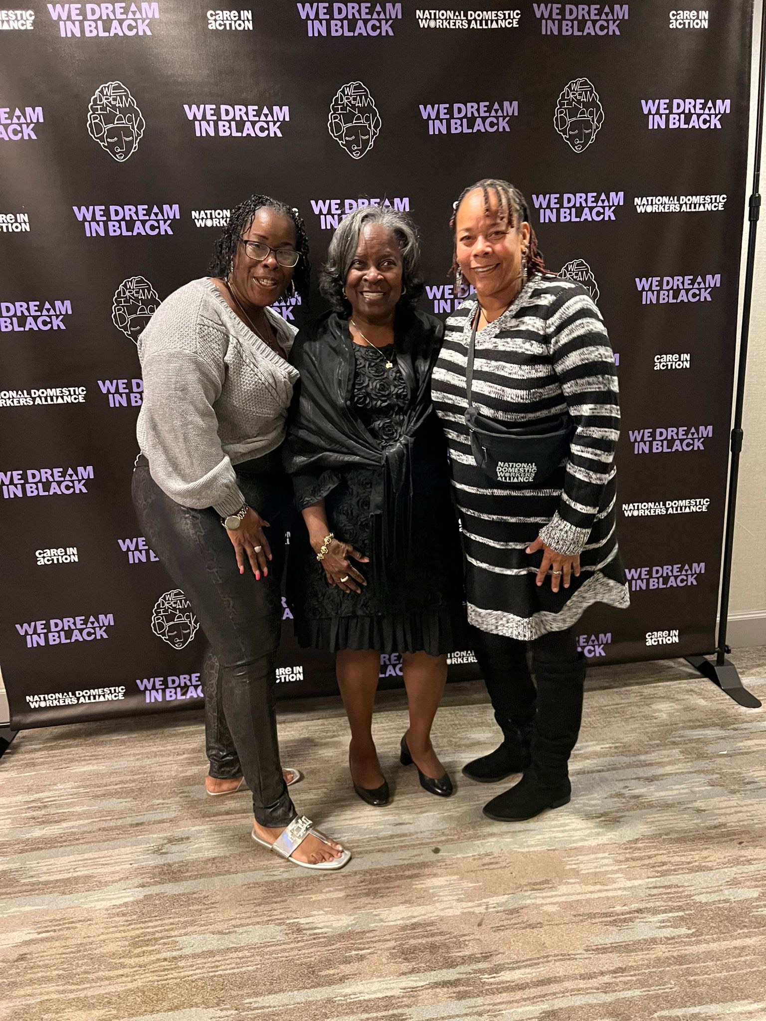 Three women posing against WeDiB backdrop.